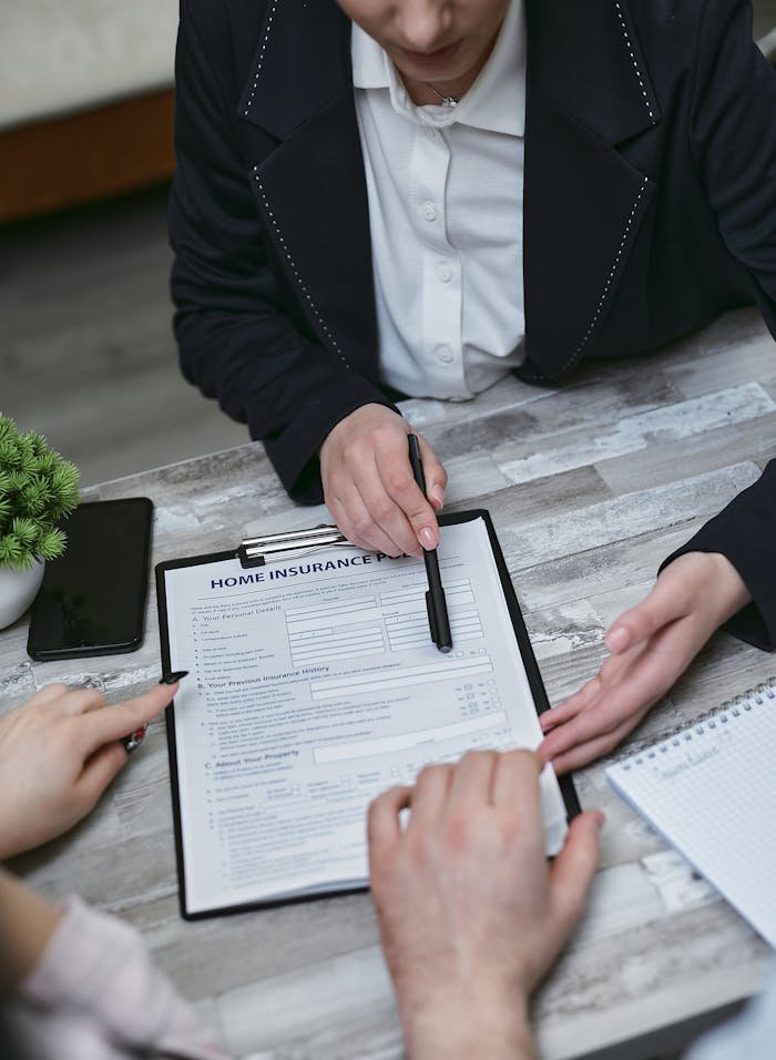 Home An agent and clients discussing paperwork for home insurance at a meeting table.